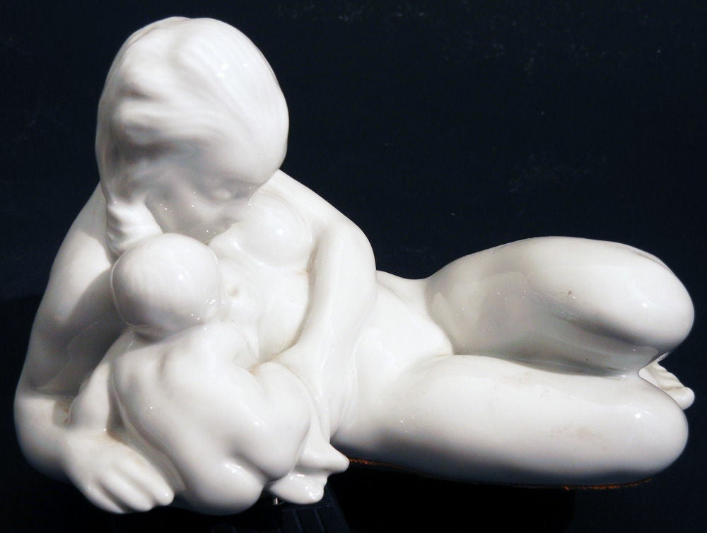 Fabriquée de manière exquise par Bing et Grondahl en 1913, cette figurine en porcelaine blanche de Kai Nielsen reflète sa fascination pour les figures féminines qui semblent être des mères pour les humains et les animaux marins.  Ici, elle enlace