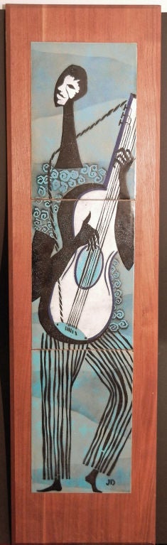 Superbly crafted and beautifully mounted on a gorgeous plank of American walnut, this class midcentury enameled panel depicts an African American man playing the guitar, all on a field of pale blues and grays.  The lambswool texture of the player's