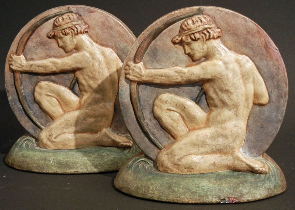 This pair of painted ceramic bookends, featuring a kneeling nude male archer, are very fine and rare. They were produced by the Compton Potters' Arts Guild, founded in Surrey, England, by Mary Fraser Tytler.  After World War II, Compton produced