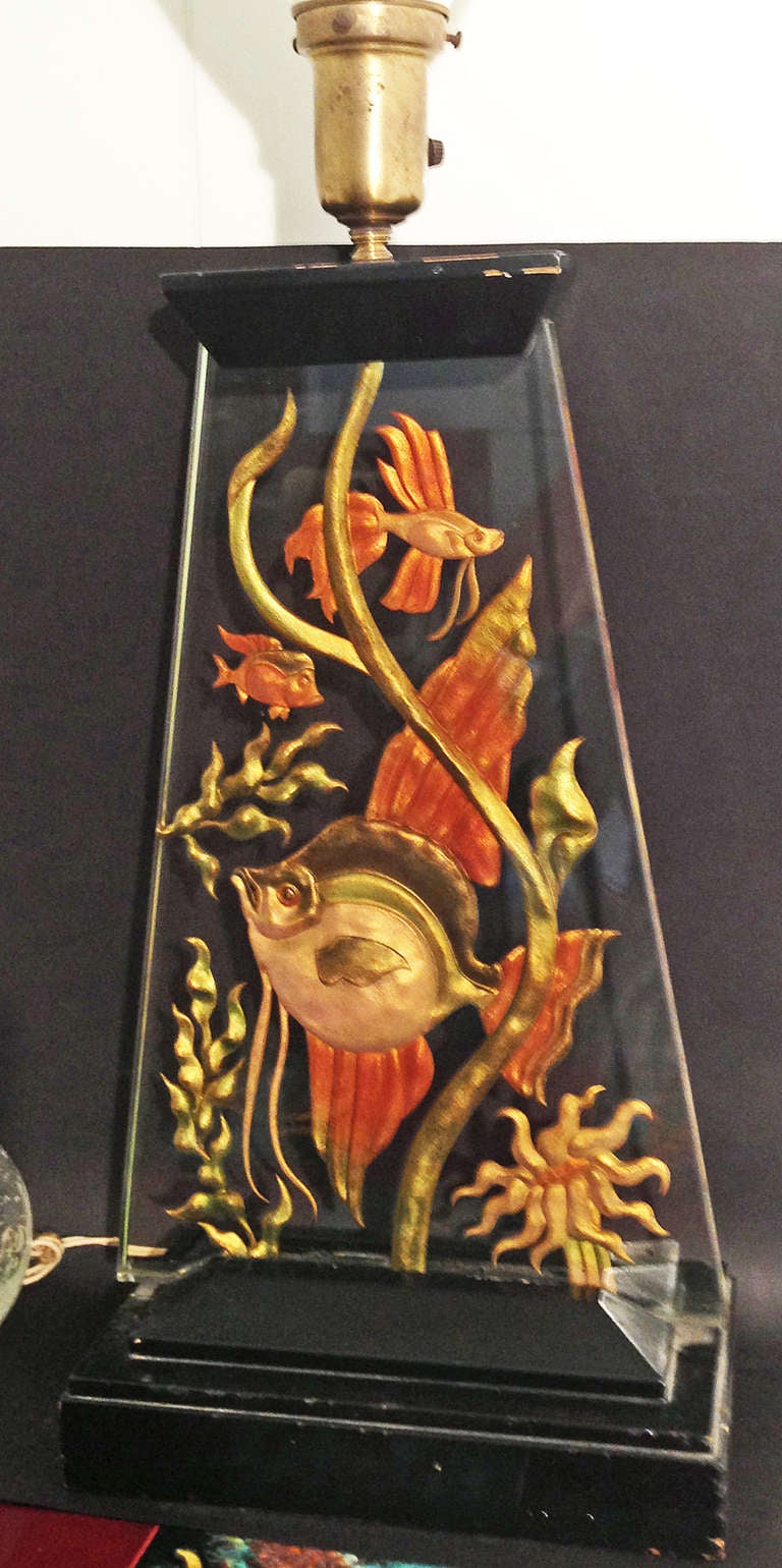 This rare and extraordinary lamp, composed of molded, gilded and enameled glass in a trapezoidal shape, depicts angel fish, Siamese fighting fish and another exotic specimen swimming among seaweed and a sea anemone.  A spectacular example of Art