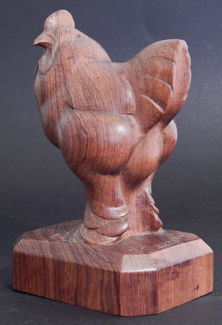 Sculpted from a block of boldly grained walnut, this depiction of a barnyard cockerel, in all his prideful finery, was carved in a strong, Art Deco manner by George Laurent.  The mass and planes of the rooster's body, and the details of the feathers