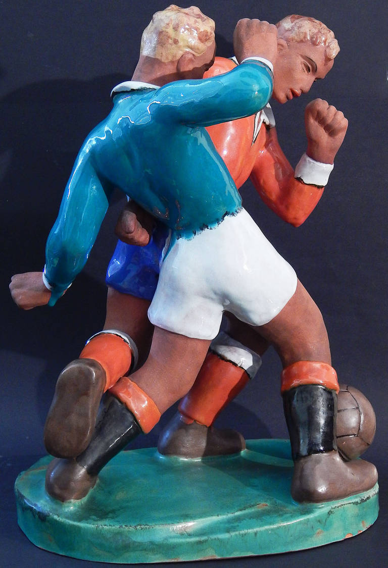 The only example we have ever seen, this large and boldly glazed sculpture of two soccer or football players depicts the moment when they are fighting for the ball. The interlocking figures of the two players, their total concentration on the ball
