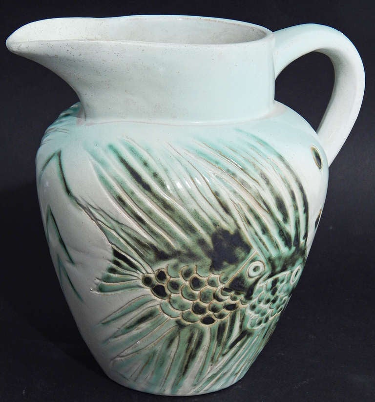 Produced by one of America's great potteries in the Arts and Crafts and Art Deco periods, this unique, sculpted pitcher depicts pairs of exotic fish with spiky fins on both sides.  The artist worked at the famous pottery of the University of North