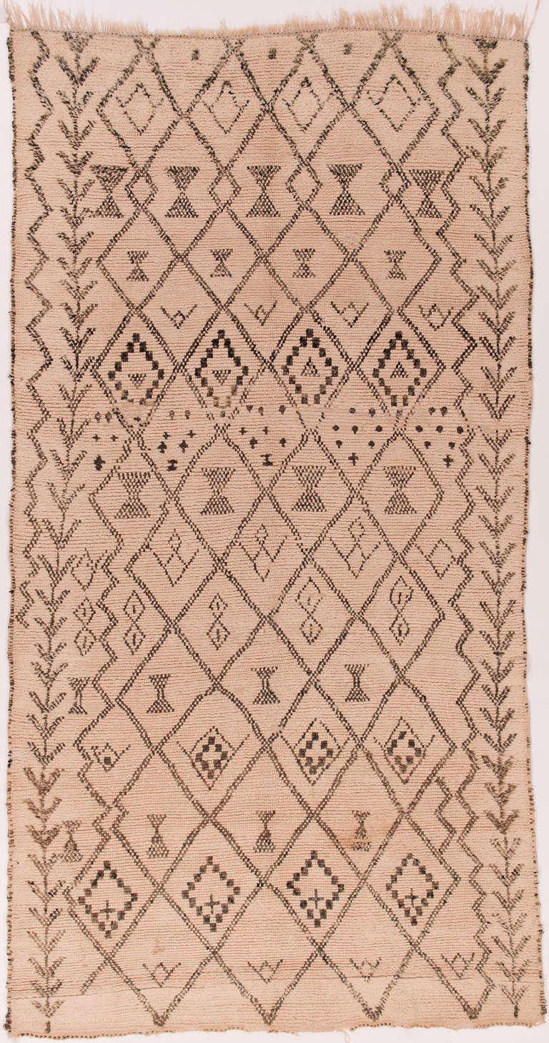 a great Berber rug using traditional motifs. This is an old and authentic Beni Ourain rug probably woven in the 1930s. The pattern seems neolithic and connected to fertility cult imagery. It is in good condition for its age but should not be
