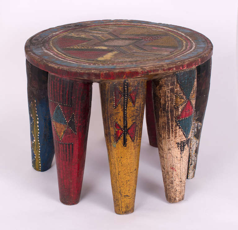 A fantastic Nupe stool from Nigeria carved from single blocks of wood. Most Nupes are Muslim and their art is, therefore, abstract. This Nupe is hand-painted with primary colors painting and carving on dense wood. It stands on its eight original