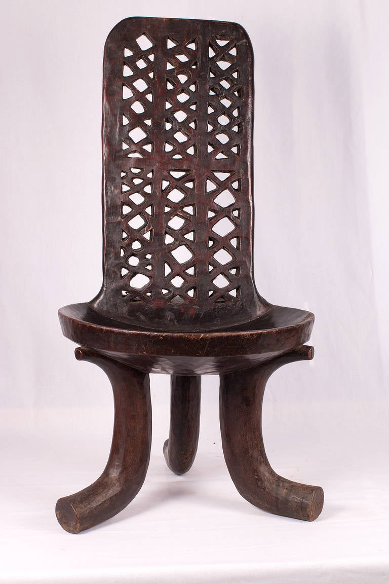 This beautiful three-legged chair is made from one piece of wood. It is adorned with a laddered back.