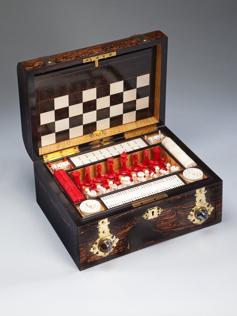 An outstanding and fine quality Victorian patent games compendium. 

Richly veneered in coromandel wood with lacquered gothic revival brass mounts. Enriched with agate cabochons and spring release for bottom drawer. Contains 4 packs of cards, 1 set