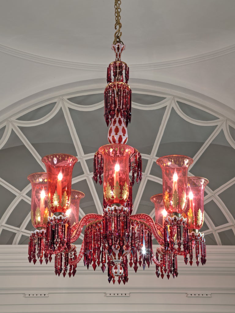 A red, white and gilt overlayed chandelier, the main receiver bowl supporting eight candle arms with drip pans and storm shades, all hung with cut back Alberts and cut back spear drops. The metal work is stamped F & C Osler of Birmingham. Made for
