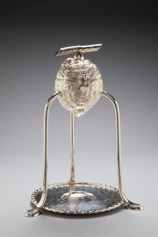 An unusual Edwardian novelty silver-plate lemon squeezer stand designed by Hukin and Heath, stamped with maker's marks and registration number, the naturalistic lemon on three curving supports, resting on a circular plinth complete with central
