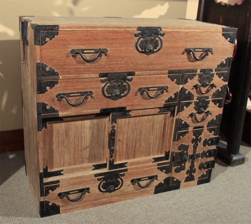 A small Japanese choba-dansu, or office chest, constructed entirely of Kiri wood (Paulownia) with wrought iron lock plates corner pieces and handles. The lock plates forged in the Mikune style with Hirute style drawer pulls.