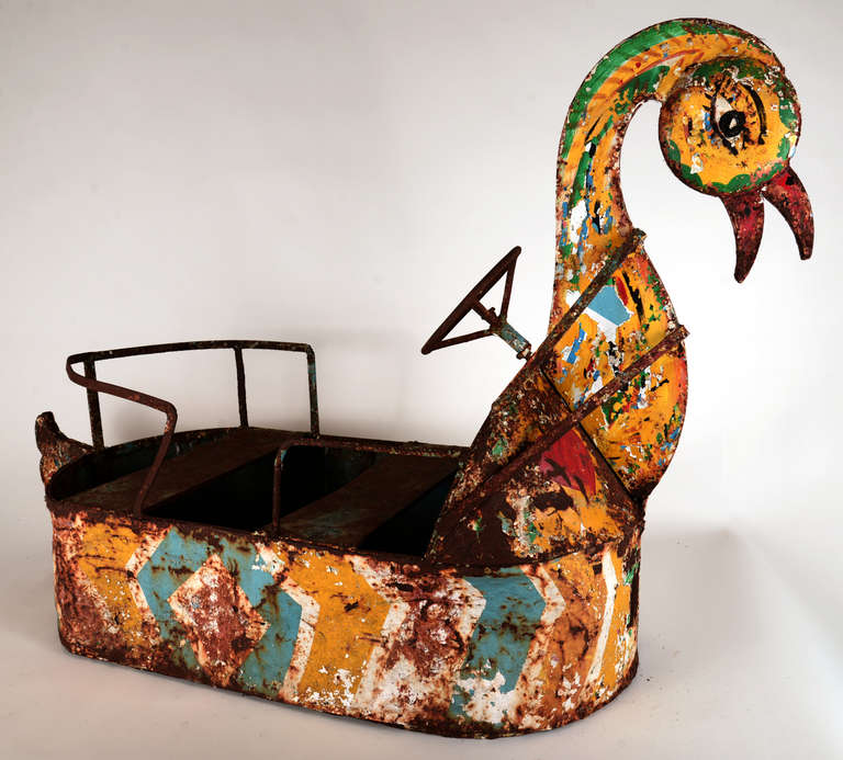 Chipped-surface multi-color steel carnival ride in a whimsical swan-like form.   Guard rails and a steering wheel intact with an overall very worn painted surface.  Originally from a Paris-area amusement park ride, found here in the United States