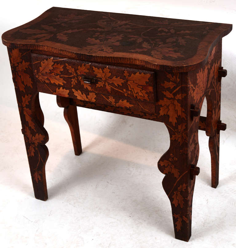 An extraordinary piece of pyrographic folk art furniture found in New England, this diminutive single-drawer desk has a scalloped top and legs, all surfaces having a wonderful oak leaf and acorn decoration done in the 