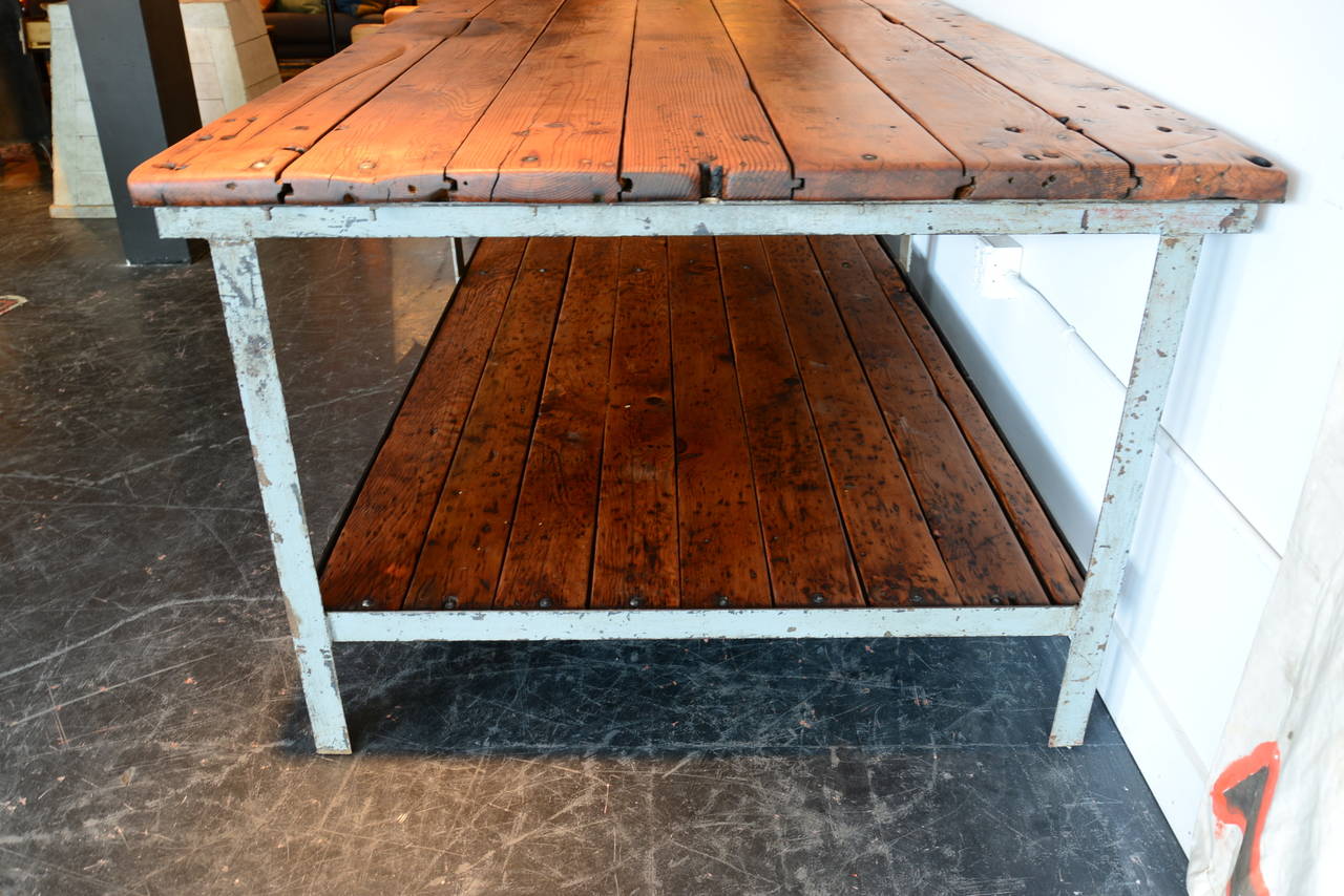 This massive bi-level table came out of a machine shop in Portland. Old growth honey colored Douglas fir planks are securely bolted into a steel frame with remnants of pale gray paint. This has been thoroughly cleaned and waxed and is ready to be