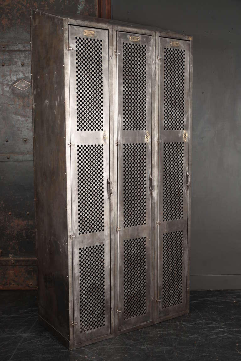 A very unusual three door industrial locker from the Lyon Metal Products Company, in Aurora, Illinois and having perforated door fronts with beautiful brass escutcheons and number plates. The handles and hinges are subtle pieces with attention to