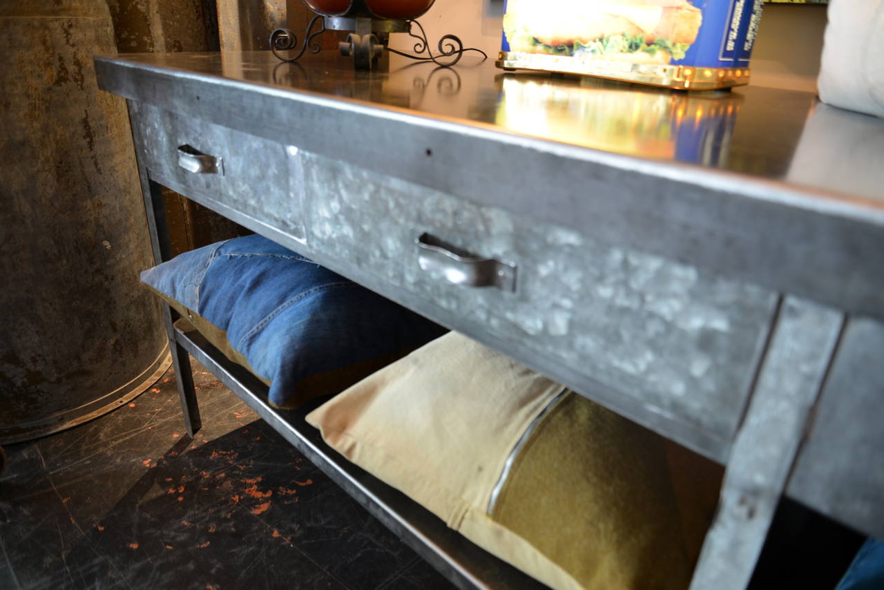 Galvanized steel table with bottom shelf and three drawers that operate smoothly. This piece has been thoroughly cleaned and waxed to show off it's amazing patina and is ready for any commercial or residential setting.