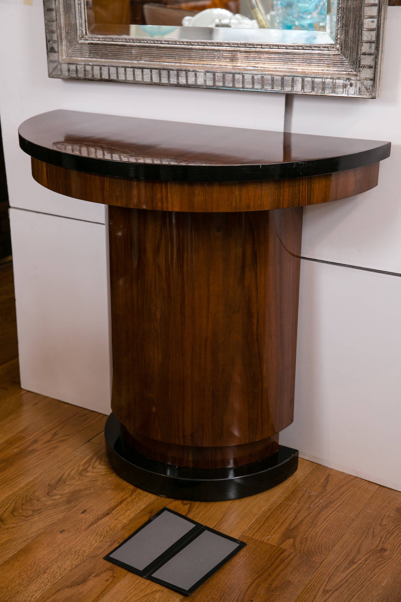 Sleek pair of demilune console tables in walnut with black lacquered detailing.