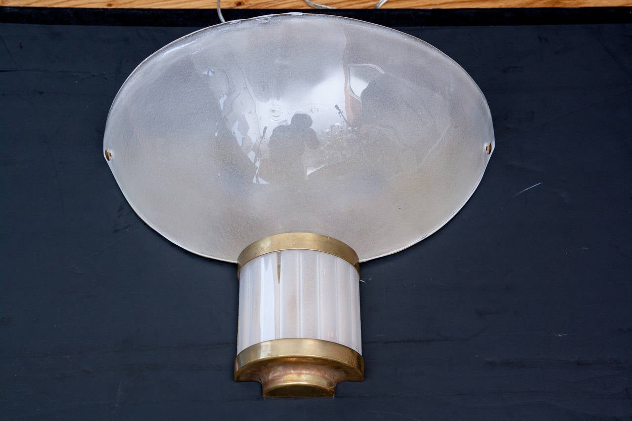 Classically restrained this wonderful vintage pair of demilune Murano wall lights are blown in a shimmery off white tone and are shown with brass fittings, marked Venini, 1950s.