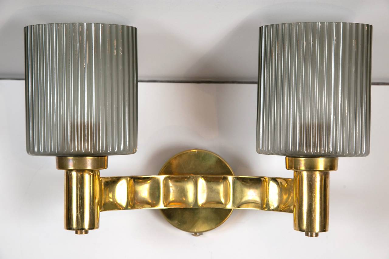 Pair of double arm brass wall lights with grey glass reeded cups.
Two pairs available.