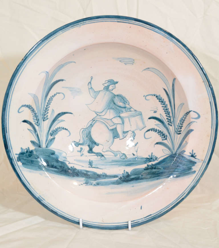 A Spanish faience charger decorated in azure blue with a drummer on horseback. His horse rears up as the drummer rides away.
With marks from Puente Del Arzobispo.
Similar in many respects to the blue and white Dutch delft of the late 18th and