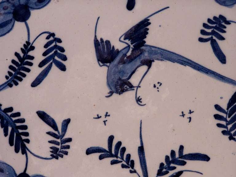 An English delft blue and white charger with a well painted scene of a bird and butterflies above a garden. The design combines the bold brush strokes typical of delft with the sophistication of the Chinese inspired design.  
The boom time for