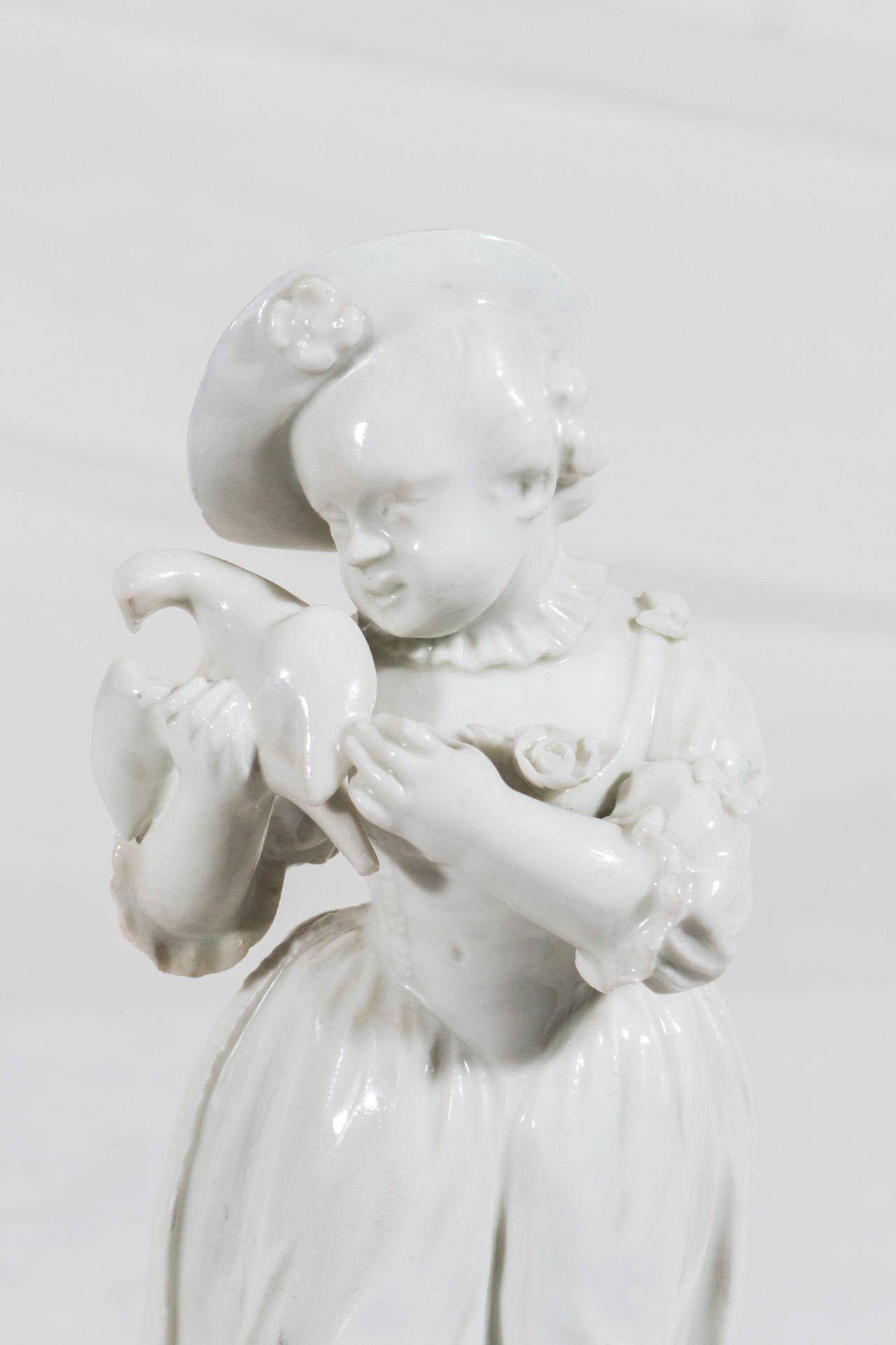 A mid-18th century Frankenthal porcelain figure of a young girl dressed in period costume holding a dove. She is posed with her head tilting to the right, the right leg slightly forward, the bird cradled in her right arm.