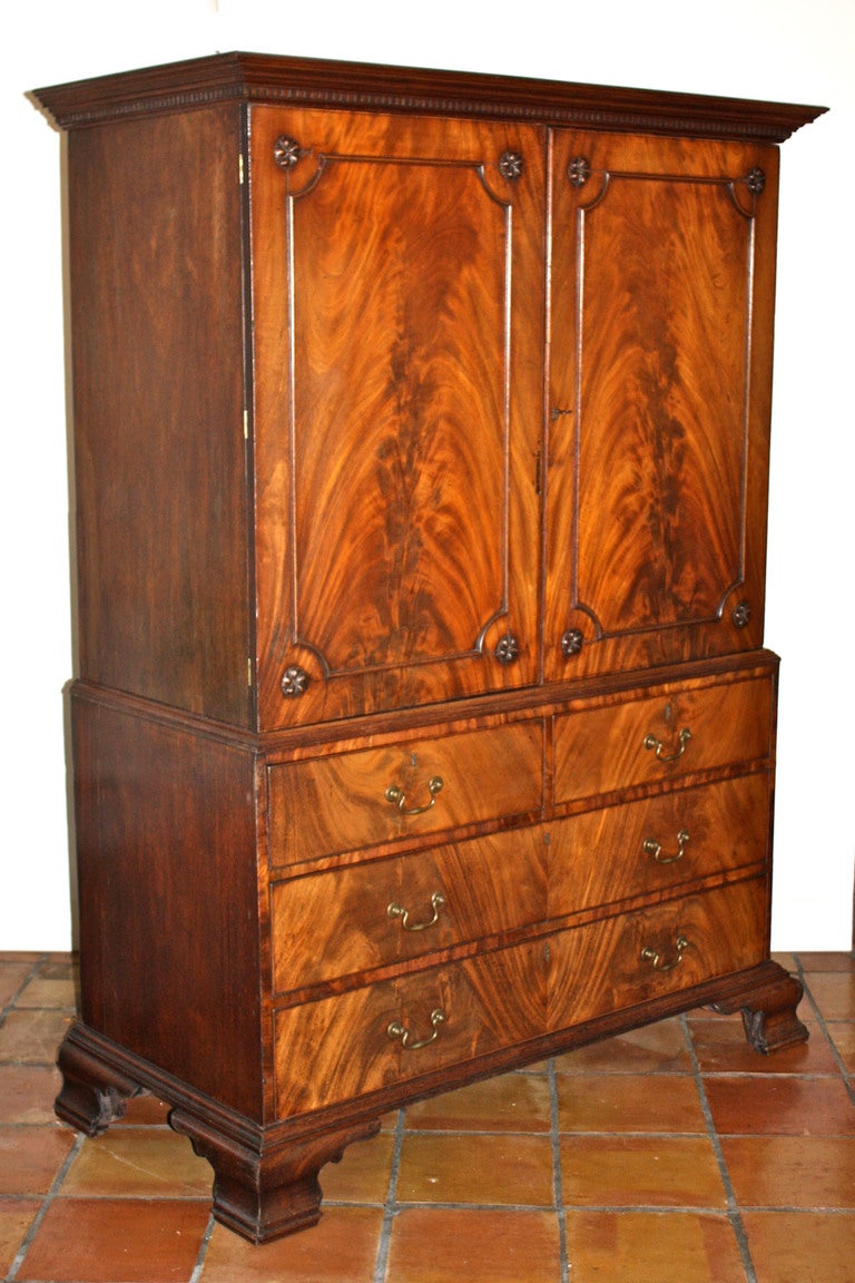 In the Chippendale manner,  an exceptionally grained and colored mahogany linen press.  The two upper case doors enclose three original sliding shelves.  The lower case contains four drawers, two over two; with intervening dust boards.  The cornice