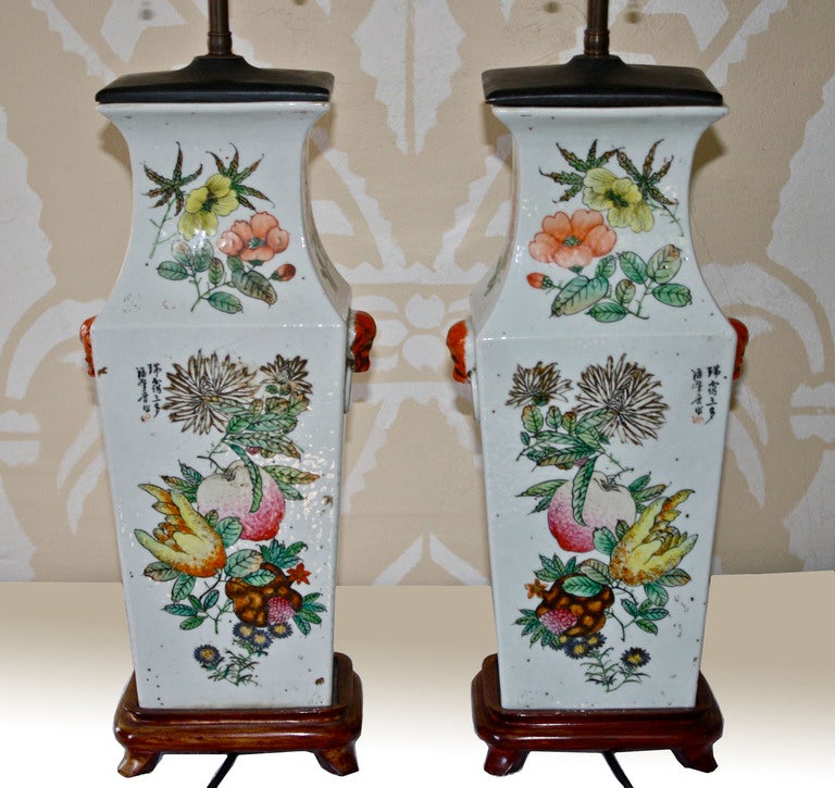 A pair of Chinese orange peel porcelain tapering rectangular vase lamps, with lion head ringed-mouth side mounts.  Eight courtiers on each front face; non-identical lamp to lamp.  The sides are heavily inscribed.  The front and rear faces are corner