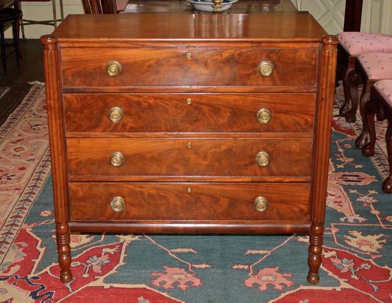 A mahogany Sheraton manner, reeded turret front-cornered chest of four drawers; raised on four ring turned legs.  Strikingly grained crotch mahogany drawer fronts and original brass pulls.  This chest and its companion step-back chest which we