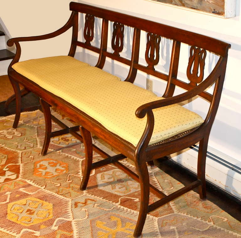An Italian cane seated fruitwood quadruple lyre back settee and accompanying side chair. The lyre forms are actually pairs of swans' necks with a central inlaid column, simulating strings. Klismos legs with h-stretchers on both settee and chair.