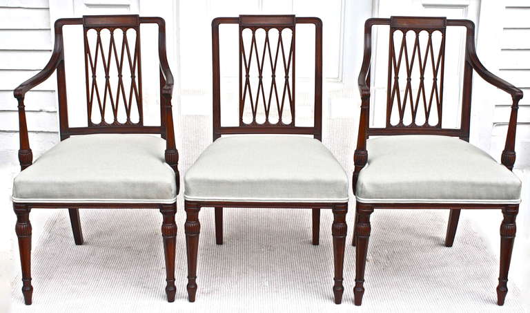 Two armchairs and six side chairs of the late 18th century Thomas Sheraton manner and design.   Hand made of heavy dense mahogany, likely Santo Domingo or comparable; the finely detailed carvings and turnings are crisp and meticulously executed. 