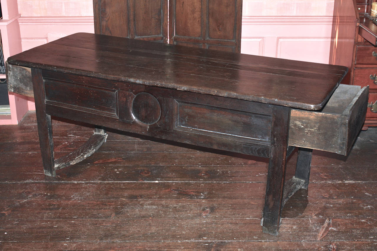 A hand hewn George I period chestnut refectory preparation or serving table, which may have been originally made to serve as a kitchen dough table; with apron drawers at each end for dough storage.  Its end legs are joined by concave flat