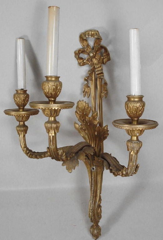 A pair of 'three candle' electrified ormolu wall sconces, made in Spain in the 18th century style of Louis XV of France & Carlos III of Spain; both of the House of Bourbon with proximately concurrent reigns.