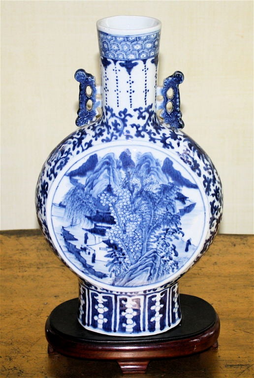 In the manner of a 17th Century Ming Dynasty flask, its center medallion is<br />
a warm water spring pond; with opposite landscape views on either side.  Tall cylindrical neck with pierced chilong scrolling handles, basketweave border, scrolling