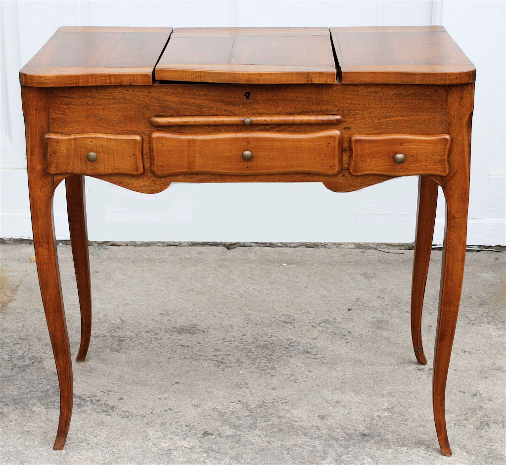 In the style of provincial fruitwood furniture of the 18th century; a diminutive<br />
dressing table usable as a bedside night stand.  Two flip-top compartments,<br />
two drawers (plus one 'faux' for balance), a leather surface 'brushing