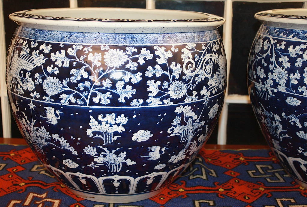 An unmarked cobalt blue and white pair of sizable planting pots or jardinieres, in the late Kangxi style; with flora, fauna, and varying geometric and foliate borders.  Safely dated as very late Qing.  A Sothebys Arcade auction sticker remains.