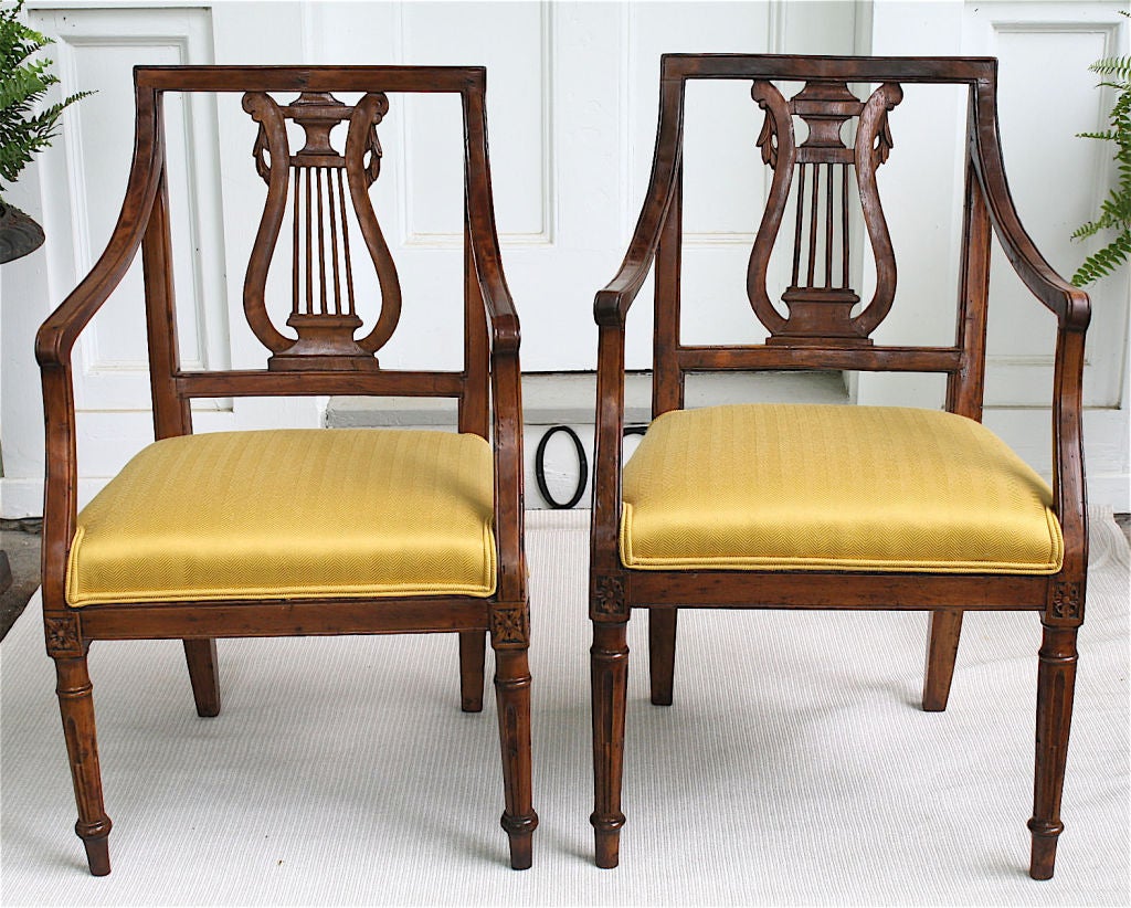 Of Nord-Ovest provincial origin; a 'near pair' of walnut lyre back armchairs.  In the manner and period of Louis XVI fauteuils, the front legs are stop-fluted and topped with floral paterae.  The lyre backs and arms are precursor to Directoire.  Not