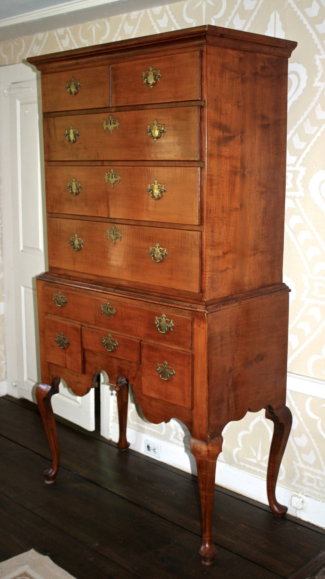 An earliest Townsend Shop flat-topped high chest or 'highboy', of subtle tiger and figured maple; with an upper case of five drawers and a lower case of four drawers, raised on Queen Anne pad-footed legs. The lower case drawer configuration,