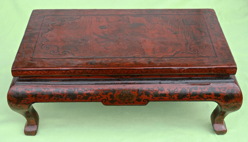 A Chinese oxblood lacquered 'Kang' low table.  Cabriole legged with exceptionally intricate pen work.  Kangxi Period of the Qing Dynasty; late third quarter of the 18th century.  Originally made as an accessory table for a Lo-Han chamber bed.  The