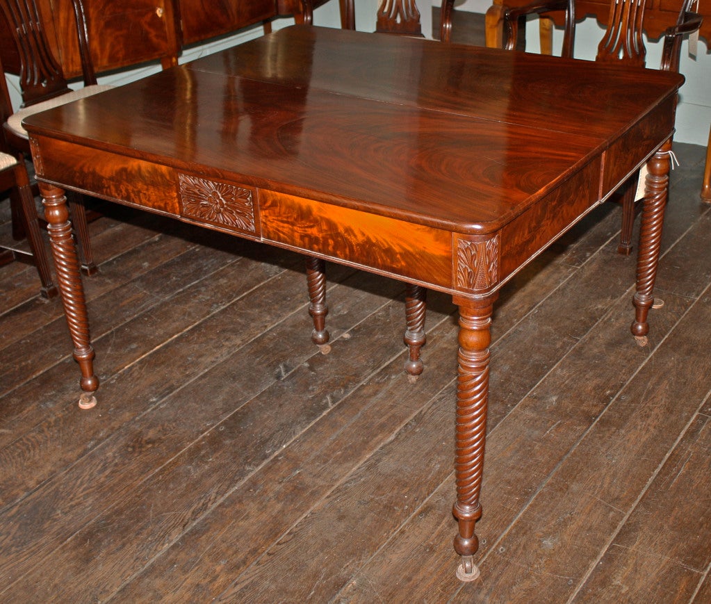 Salem, Massachusetts Classical Period Cuban Mahogany dining table with specimen 'cathedral grained' top, hand-carved foliate trimmed end and corner plaques; and twist legs ending in casters. The corner and interior support legs are unobtrusive to