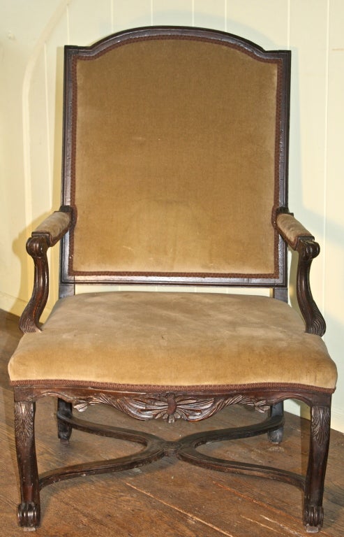 A hand-carved walnut open armchair with 'X' or flat Curule-form stretchers joining its four legs; made during the period between the reigns of Louis XIV and Louis XV (1715-1723), when Philippe d'Orleans was Regent. Tablet-back crest rail and