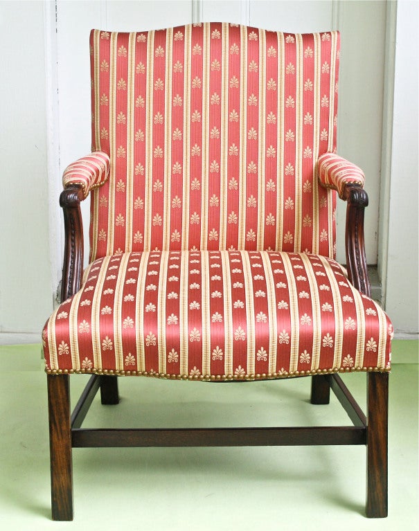 An 18th century Georgian mahogany upholstered open armchair with serpentine back crest and seat front.  Inward chamfered square Marlborough legs, raking to the rear; attached by three stretchers, and a fourth dovetailed cross stretcher.  Finely