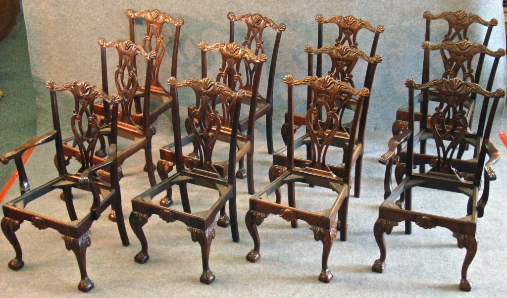 A 'long' set of 12 mahogany dining chairs, with two arm chairs and ten side chairs;    Philadelphia Chippendale manner.  Foliate decorated serpentine crest rails 'eared' in small shells, and centered with a larger shell cartouche. Pierced vasiform