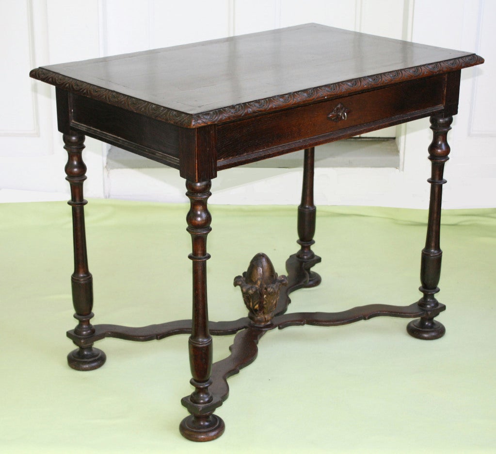 A Louis XIV period highly polished walnut and oak 'desserte' or side table with single lockable drawer, notch carved bullnose, paneled frieze, on four baluster turned legs, with crossed stretchers centered with a foliate bulb; on bun feet.  Ex: the