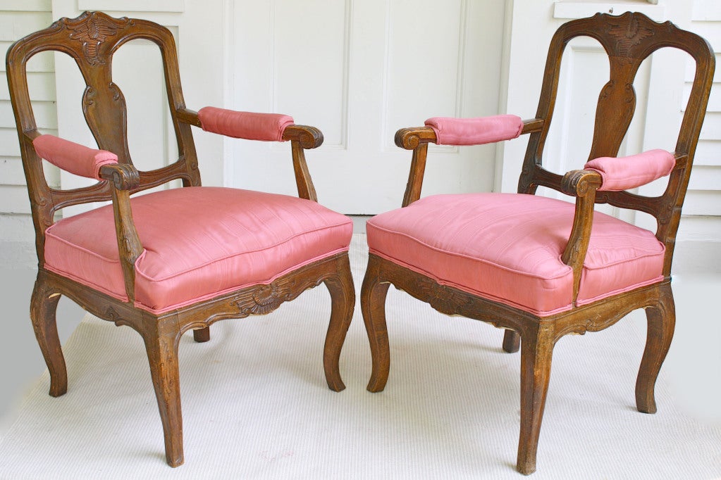 A 'near pair' of Nord-Ovest Italian transitional Baroque to Rococo, carved walnut poltrone (armchairs).  Slight irregularities in cartouches, back splats, scrolls, volutes, and foliate carved knees only on one chair; all consistent with the