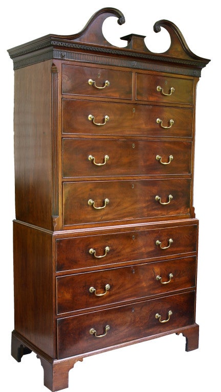 An eight drawer Georgian chest on chest, OF HIGHLY DESIRABLE SMALLER SCALE, in richly grained and colored mahogany; surmounted with a graceful and meticulously detailed hand-carved pediment, centered with a porcelain plinth. The upper case with