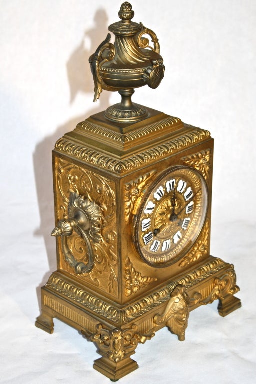 A Napoleon III period gilt bronze encased Second Empire mantle clock. The Roman  coin-like plaque on its top urn and the Egyptian masque at its plinth, harken back to the Ancient Roman Empire.  Its movement plate inscribed 