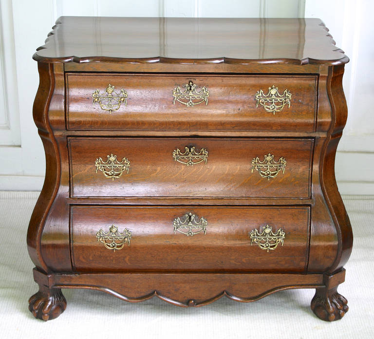 A Continental three drawer 'bombe' oak commode in the Rococo manner. Raised on ball and claw front feet with plain bracket feet to the rear; the original ormolu filigree baled pulls, escutcheons, and locks appear to be in tact. Proportioned for a