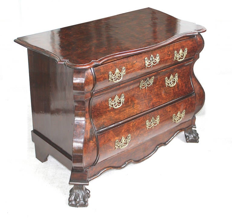 A Continental three drawer 'bombe' walnut commode in the Rococo manner. Raised on ball and claw front feet with plain bracket feet to the rear; the original ormolu filigree baled pulls, escutcheons, and locks appear to be in tact. Proportioned for a