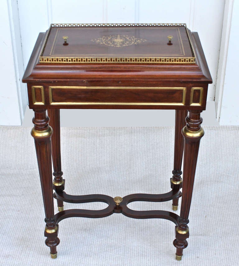 A French-polished mahogany Louis XVI manner metamorphic gueridon-to-jardiniere.  Ormolu mounts, foot caps, frieze moldings, gallery, knobs, and scrolled inlay on its removable planting container cover.  A highly decorative chair side or bedside lamp