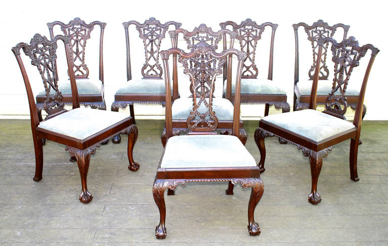 A late 19th century set of ten Chippendale Rococo-styled dark mahogany dining chairs; including two armchairs. Ribbon carved and bow-tied ornate pierced splats. Complex carved serpentine crest rails and gadrooned seat rail fronts. Cabriole legs with